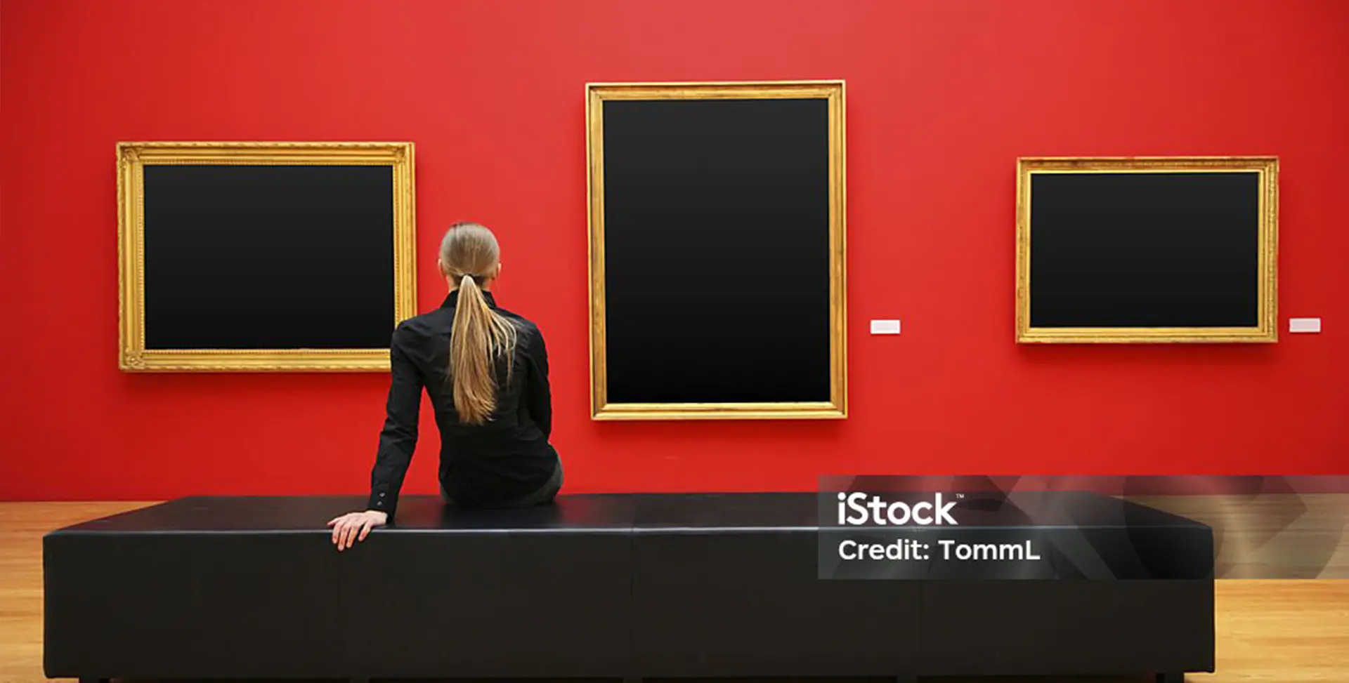 Mujer mirando cuadros sobre pared roja